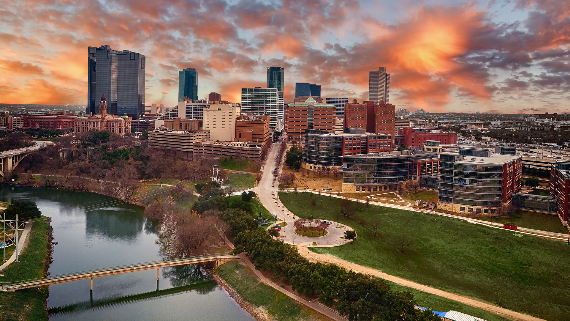 The image features a city skyline at sunset with a panoramic view of a river, park, and bridge, showcasing urban development and natural beauty.