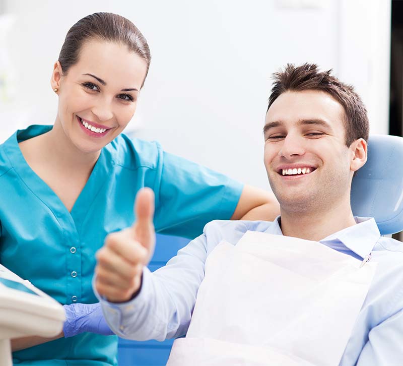 The image features a dental professional and a patient giving thumbs up in a dental office setting.