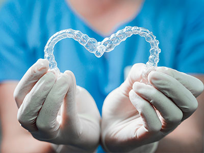 An image featuring a dental appliance designed to resemble a heart held by a person wearing medical gloves.