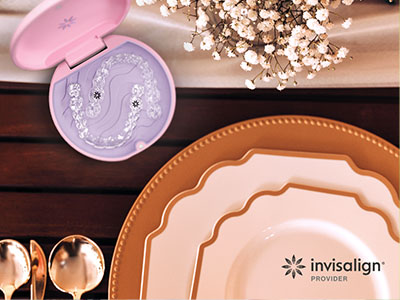 The image displays a collection of tableware including plates, bowls, and a serving tray, arranged on a wooden surface, with a pink dental impression kit prominently placed in the center.