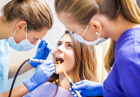 An image depicts a dental hygiene setting with a woman receiving dental care from a professional.