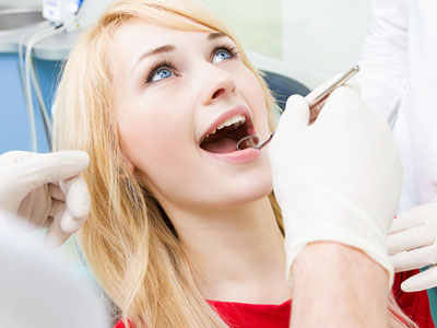 A woman receiving dental care with her mouth open wide.