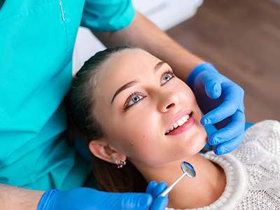 A dental hygienist performing a teeth cleaning procedure on a patient in a dental office setting.